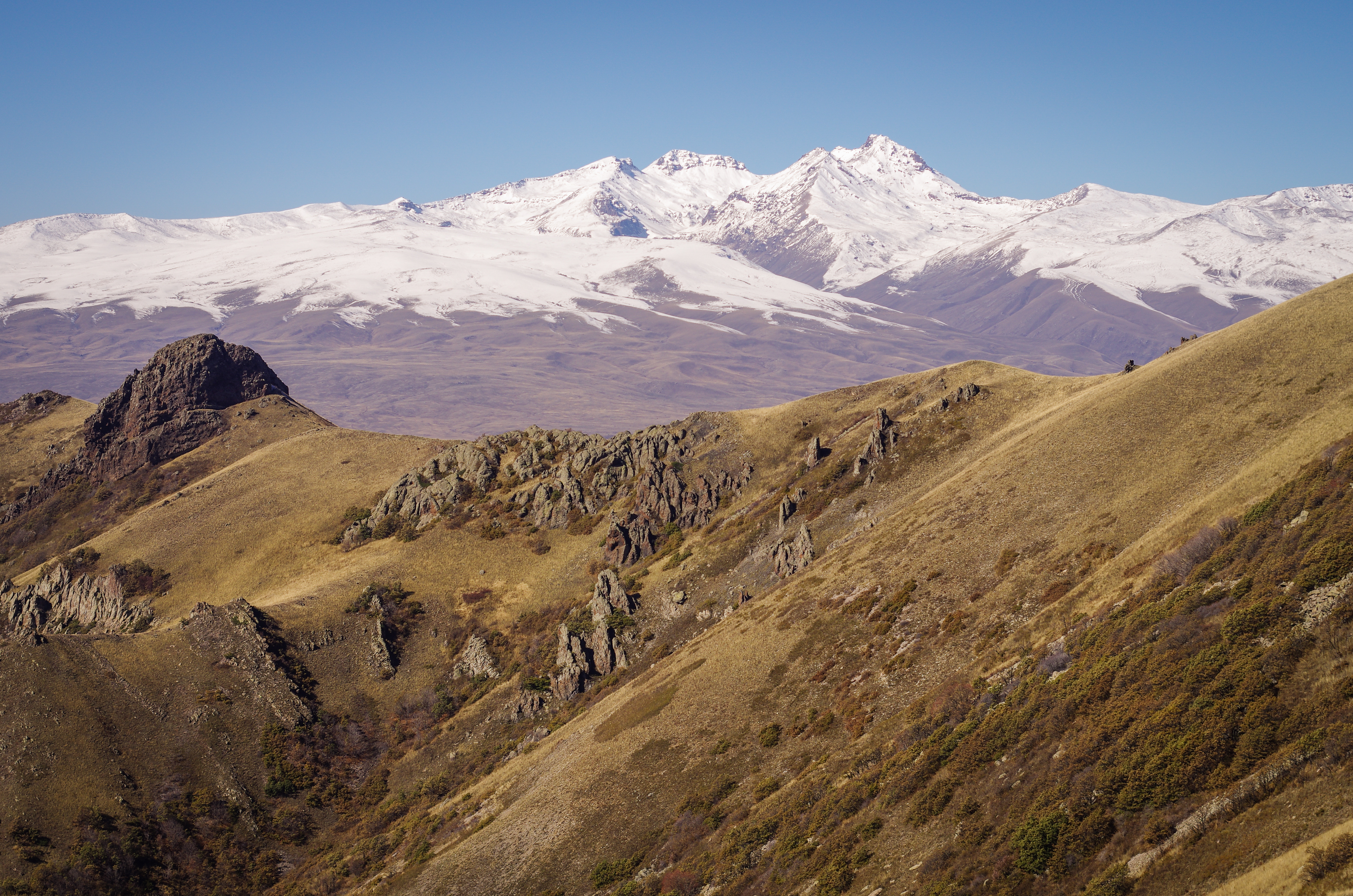 Snow-capped Mount Aragats beyond dry volcanic ridges